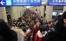 A dense crowd of commuters in winter coats fills a subway station corridor beneath signs pointing to Dongsi Shitiao and Yonghegong Lama Temple.