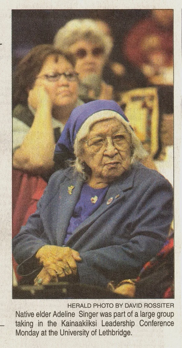 Newspaper clipping of an elder in a blue headscarf and coat; caption says Native elder Adeline Singer attended the Kainaakiiksi Leadership Conference at the University of Lethbridge.