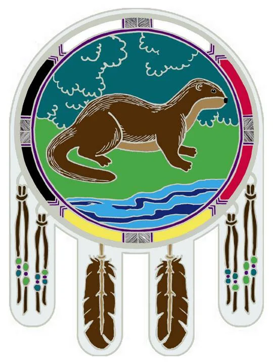 Shield-shaped emblem with a medicine wheel border in black, red, yellow and white, showing a brown otter on green grass beside a blue stream, with hanging feathers and beaded strands.