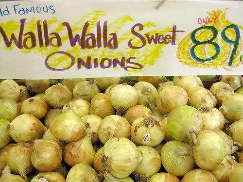 Market display of yellow onions under a hand-painted sign reading "World Famous Walla Walla Sweet Onions, only 89¢."