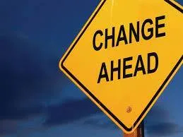 A yellow diamond-shaped road sign reading "CHANGE AHEAD" against a dark blue sky.