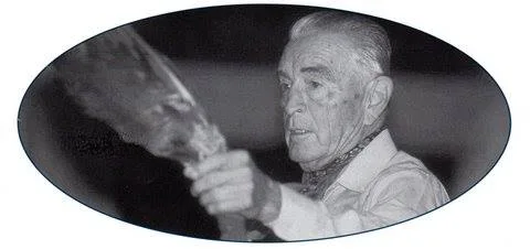 Oval black-and-white portrait of Phil Lane Sr. as an elder holding up an eagle feather fan.