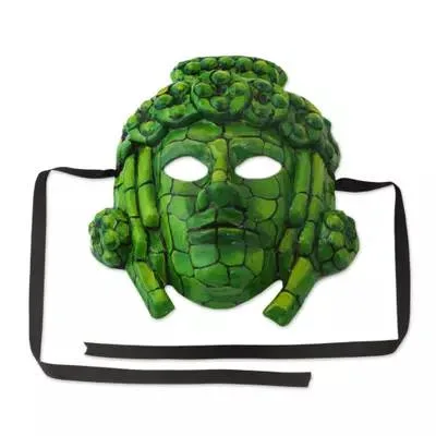 A green mask in the style of a Maya jade mosaic, with a face made of cracked tile-like pieces, ornate rounded headdress and side ornaments, and black ribbon ties.