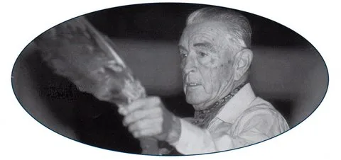 Oval black and white portrait of an elder holding up a feather.