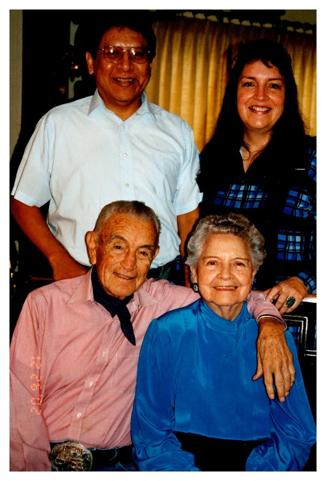 An elderly couple seated together with a younger man and woman standing behind them.