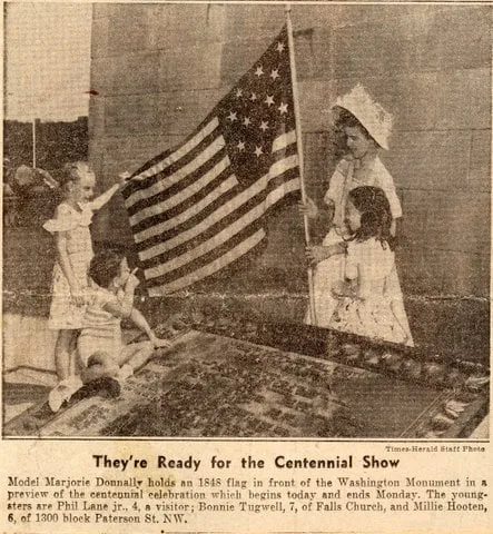 Yellowed newspaper clipping headlined "They're Ready for the Centennial Show." A woman in a bonnet holds an 1848 U.S. flag before the Washington Monument as young children, including Phil Lane Jr., age 4, gather around.