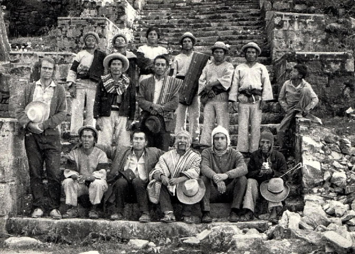 Black-and-white 1971 photograph of a group of Quechua men in hats, ponchos and woven clothing gathered on ancient stone steps on the Island of the Sun, with Phil Lane Jr. among them.