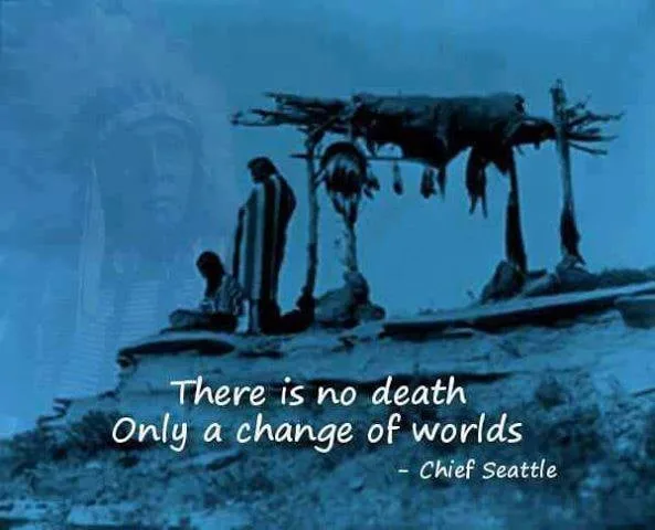 Blue-tinted historic photograph of two Native people beside a scaffold draped with hides on a rocky hilltop, a faint image of a chief in headdress behind them. Text: "There is no death, only a change of worlds" – Chief Seattle.