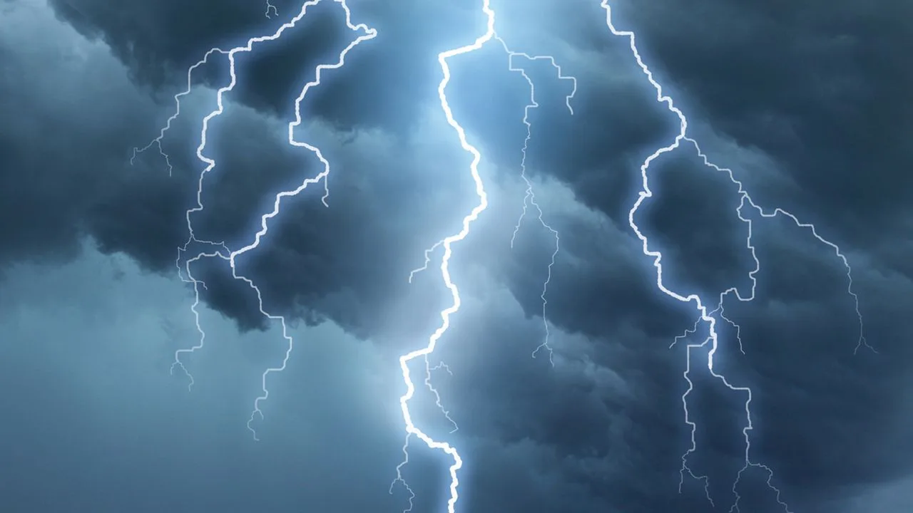 Multiple bright, branching bolts of lightning streak down through dark, swirling blue-gray storm clouds.
