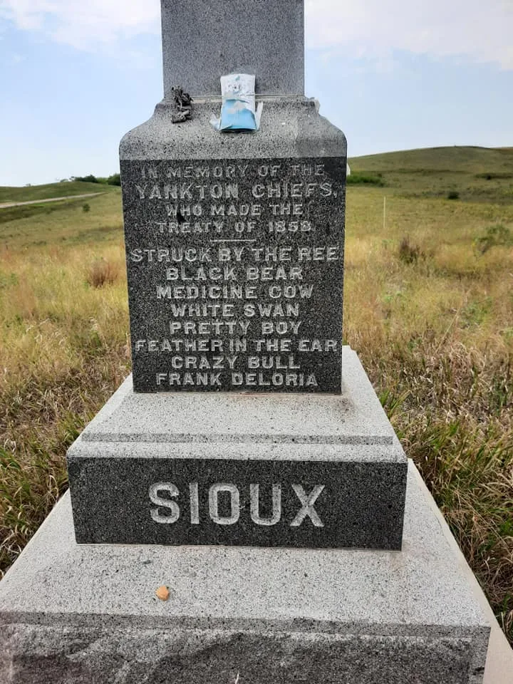 Another side of the granite monument, honoring the Yankton chiefs who made the Treaty of 1858, listing names including Struck by the Ree and Frank Deloria, with SIOUX carved on the base.