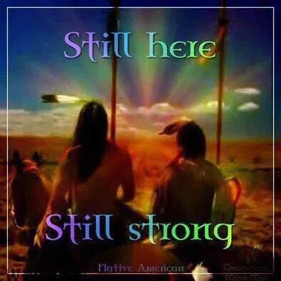 Two Native people seen from behind sit beside a horse, facing a rainbow-colored sunburst over the plains, framed by feathered staffs. Text reads "Still here, Still strong."