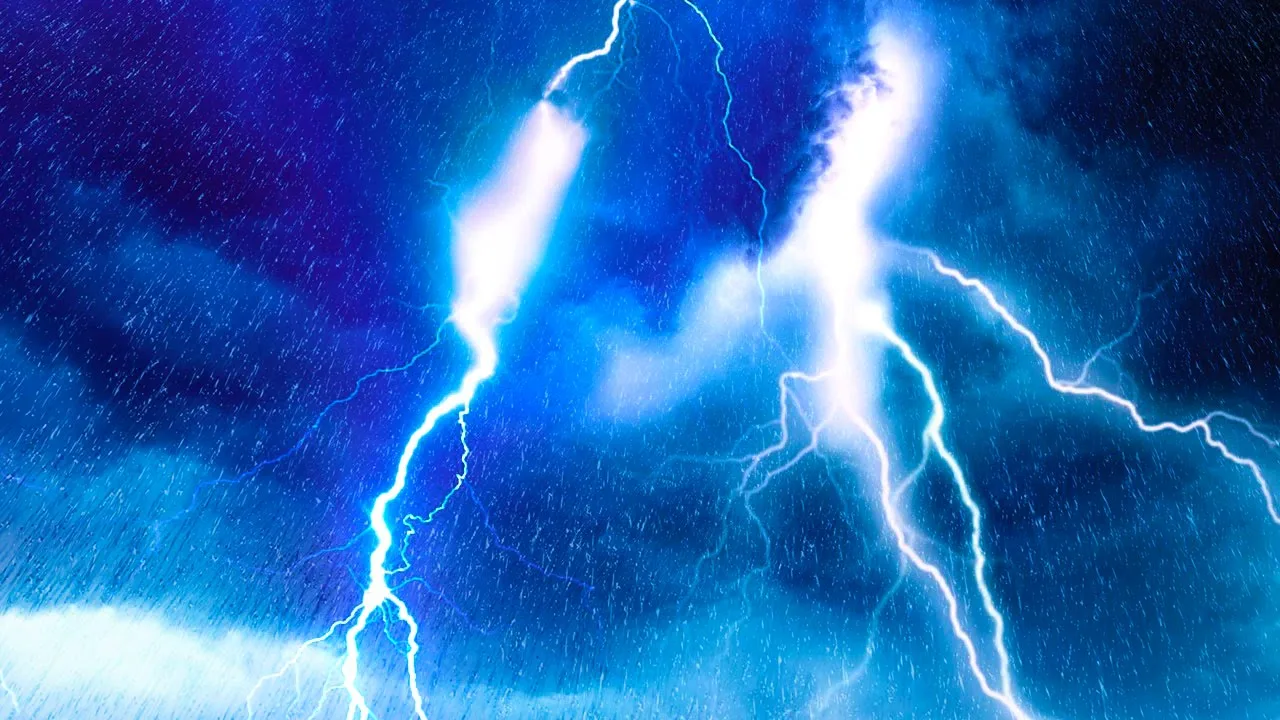 Bright forks of lightning streak through a deep blue night sky filled with storm clouds and falling rain.