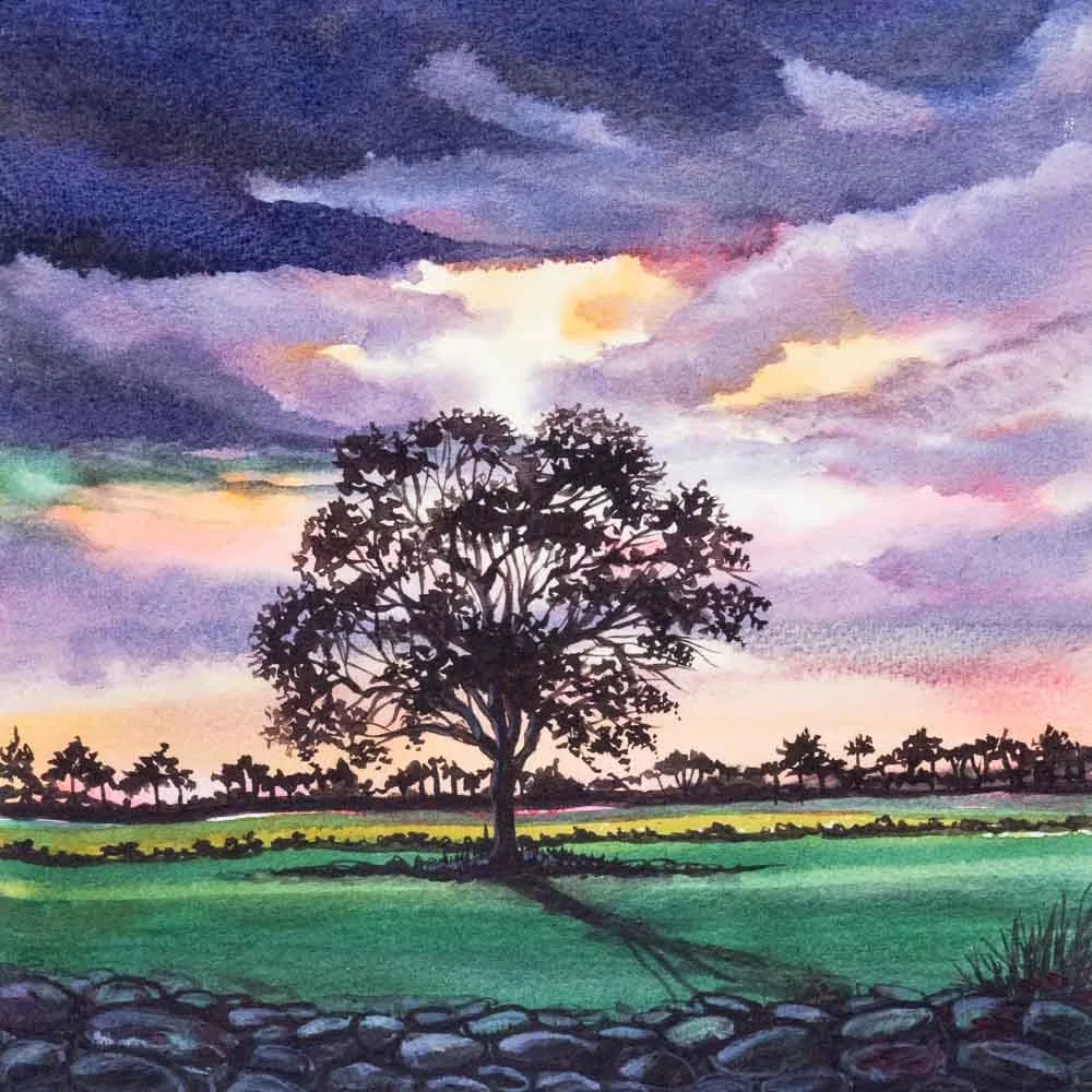 Watercolor painting of a lone tree silhouetted against a purple and golden sunset sky, standing in a green field behind a low stone wall.