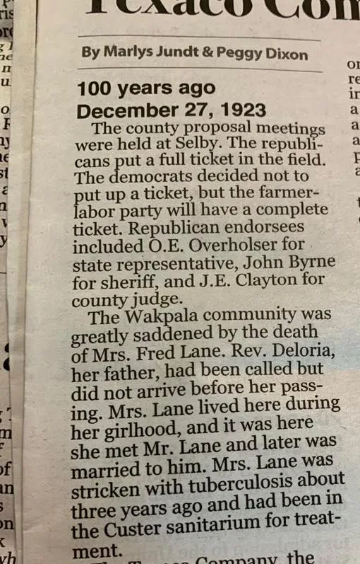 Newspaper column by Marlys Jundt and Peggy Dixon headed "100 years ago, December 27, 1923," reporting the Wakpala community's sorrow at the death of Mrs. Fred Lane, daughter of Rev. Deloria, from tuberculosis.