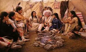 Painting of a family gathered inside a tipi around a small stone-ringed fire, with an elder in a feather headdress seated among women and children.