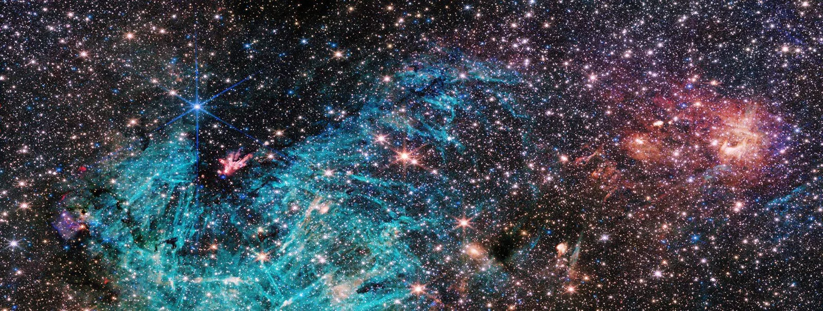 A dense field of countless stars against dark space, with swirling turquoise gas filaments on the left and a glowing reddish-orange cloud on the right.