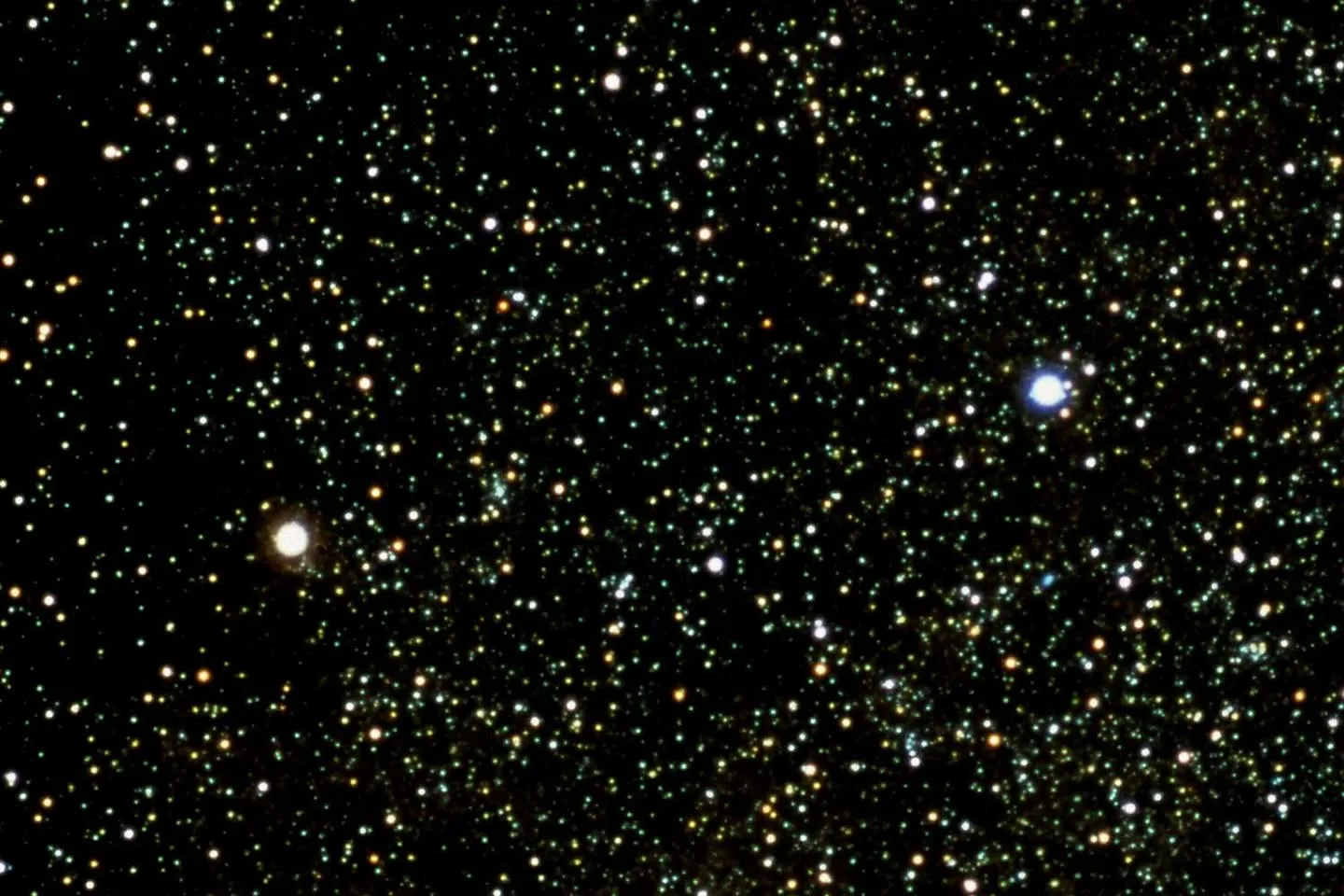 A dense field of countless stars against a black night sky, with one bright white-gold star on the left and a brilliant blue-white star on the right.